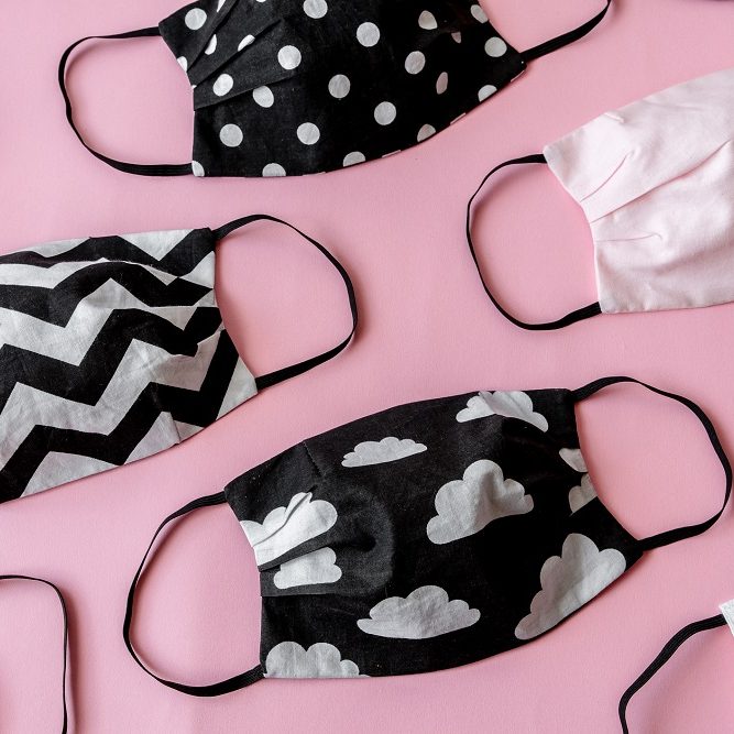 Handmade face protective masks on pink flat lay background. Reusable fabric face masks against coronavirus, covid-19 or flu. Pattern of medical mask Black and white medical masks for pneumonia outbreak