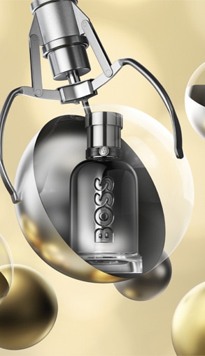 Hugo Boss parfém v elegantnom striebornom flakóne umiestnený vo vianočnej ozdobe na zlatom pozadí.