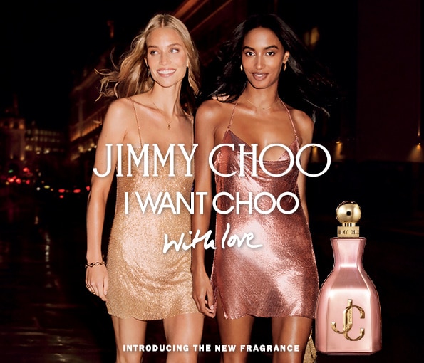 Parfém Jimmy Choo I Want Choo With Love vedľa dvoch elegantných zlatých a ružových šiat na večernom pozadí – luxusná vôňa pre špeciálne príležitosti.