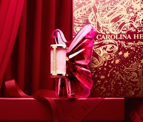 Parfém Carolina Herrera vo fľaši v tvare ružového motýľa na červenom sviatočnom pozadí s luxusnou darčekovou krabicou.